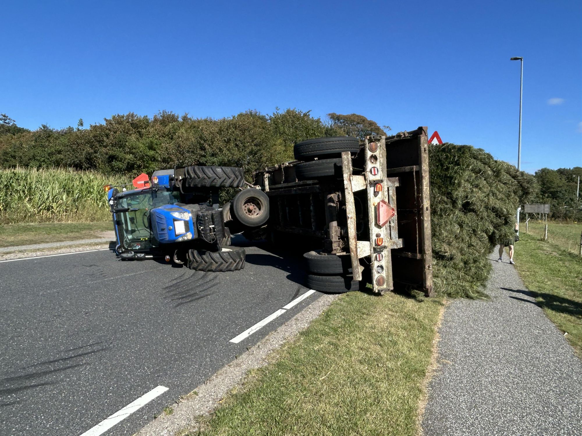 Væltet traktor med vogn på landevej efter uheld