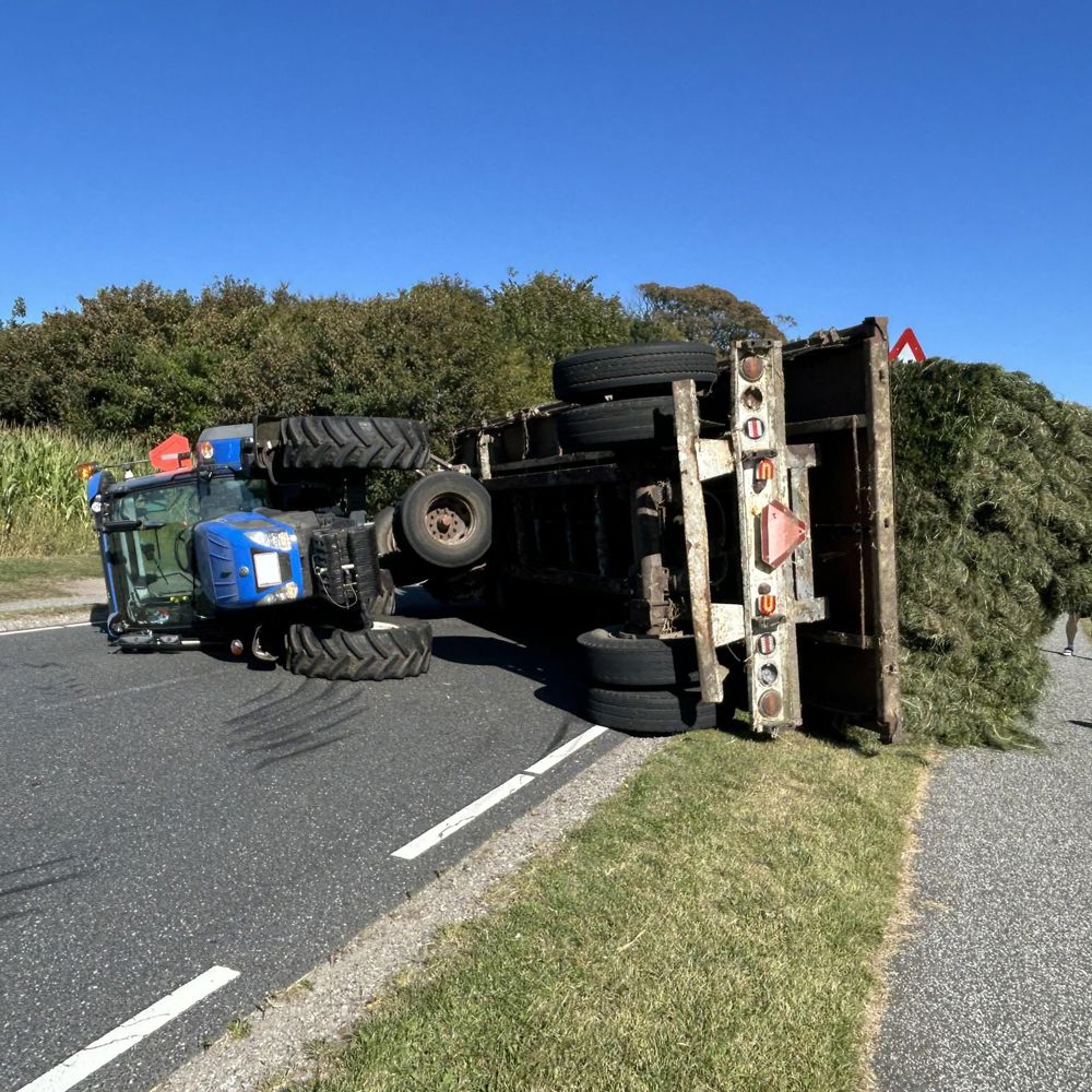 Væltet traktor med vogn på landevej efter uheld
