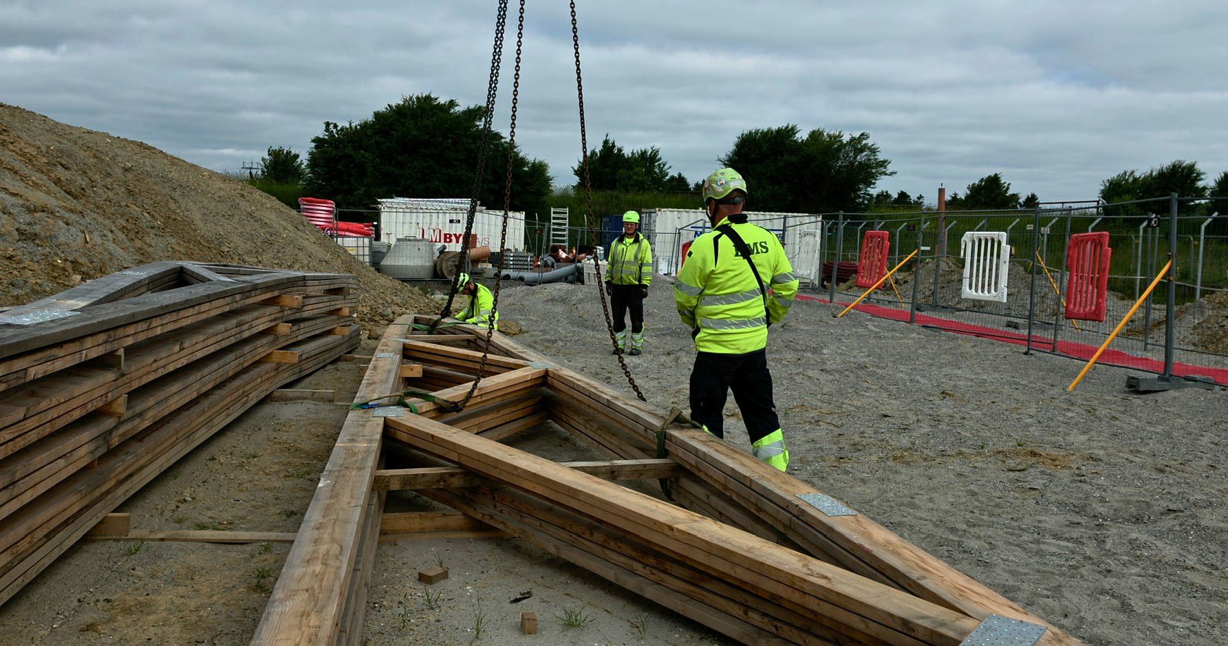 Medarbejdere rigger trækonstruktion til løft på byggeplads