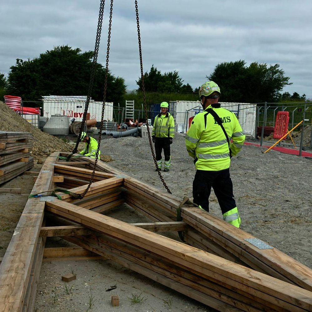 Medarbejdere rigger trækonstruktion til løft på byggeplads