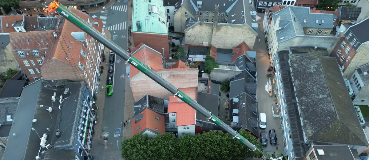 Luftfoto af mobilkranens bom, der rækker hen over Magasins bygning i Odense.