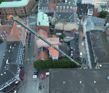 Luftfoto af mobilkranens bom, der rækker hen over Magasins bygning i Odense.