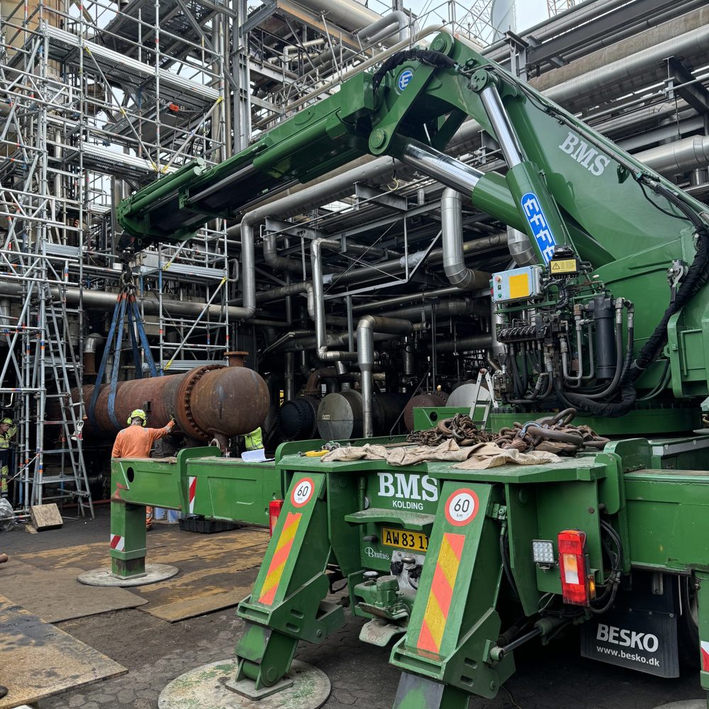 BMS lastbilkran løfter en tung cylindrisk varmeveksler ind mellem stilladser under shutdown