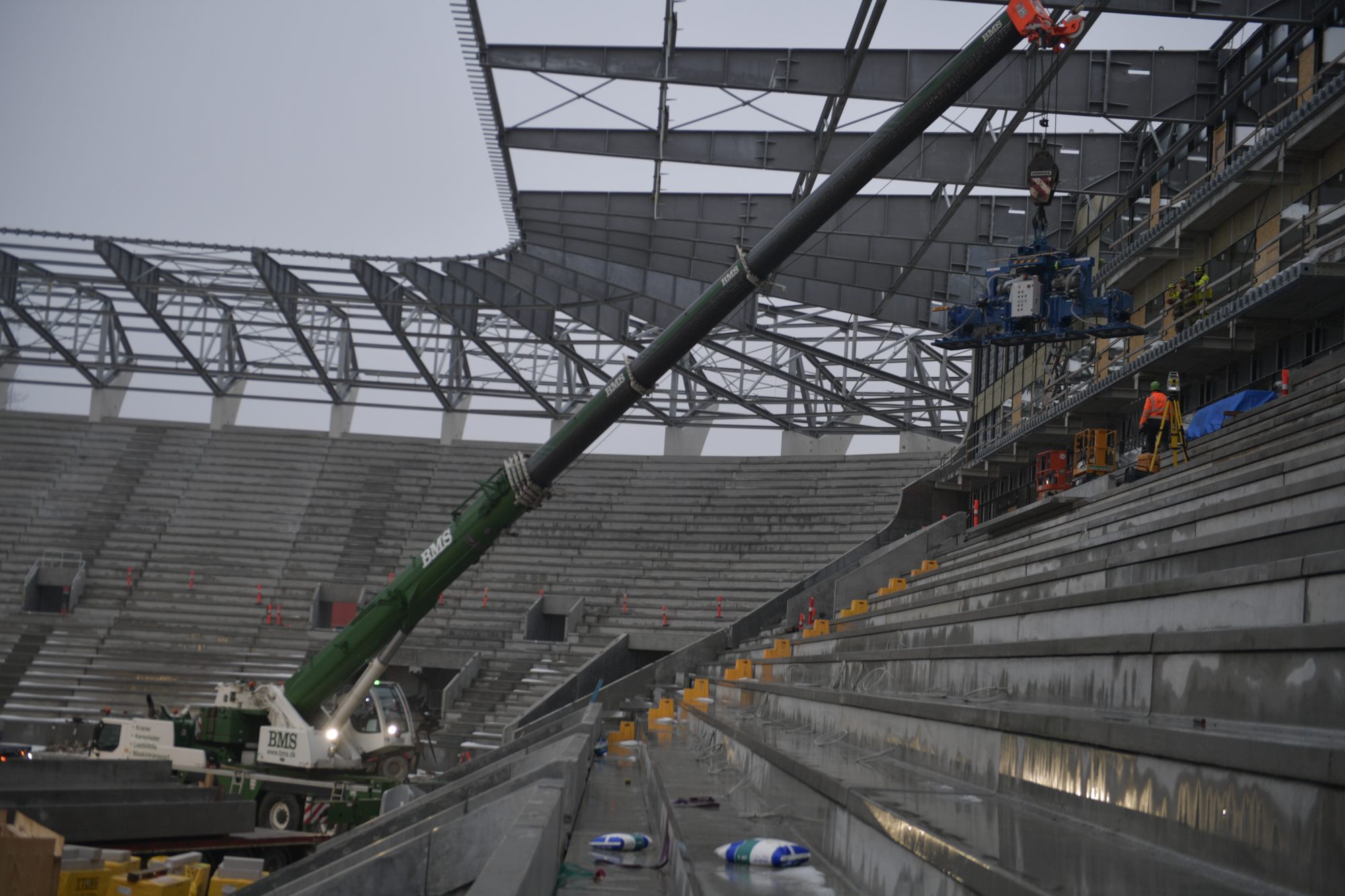 BMS-kran løfter en specialmaskine langs tilskuerpladserne under opførelse af et stadion