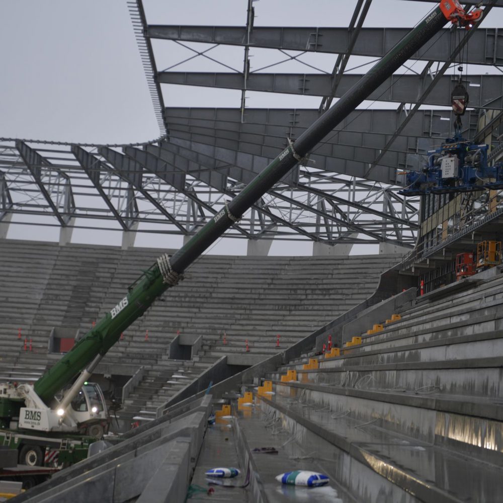 BMS-kran løfter en specialmaskine langs tilskuerpladserne under opførelse af et stadion