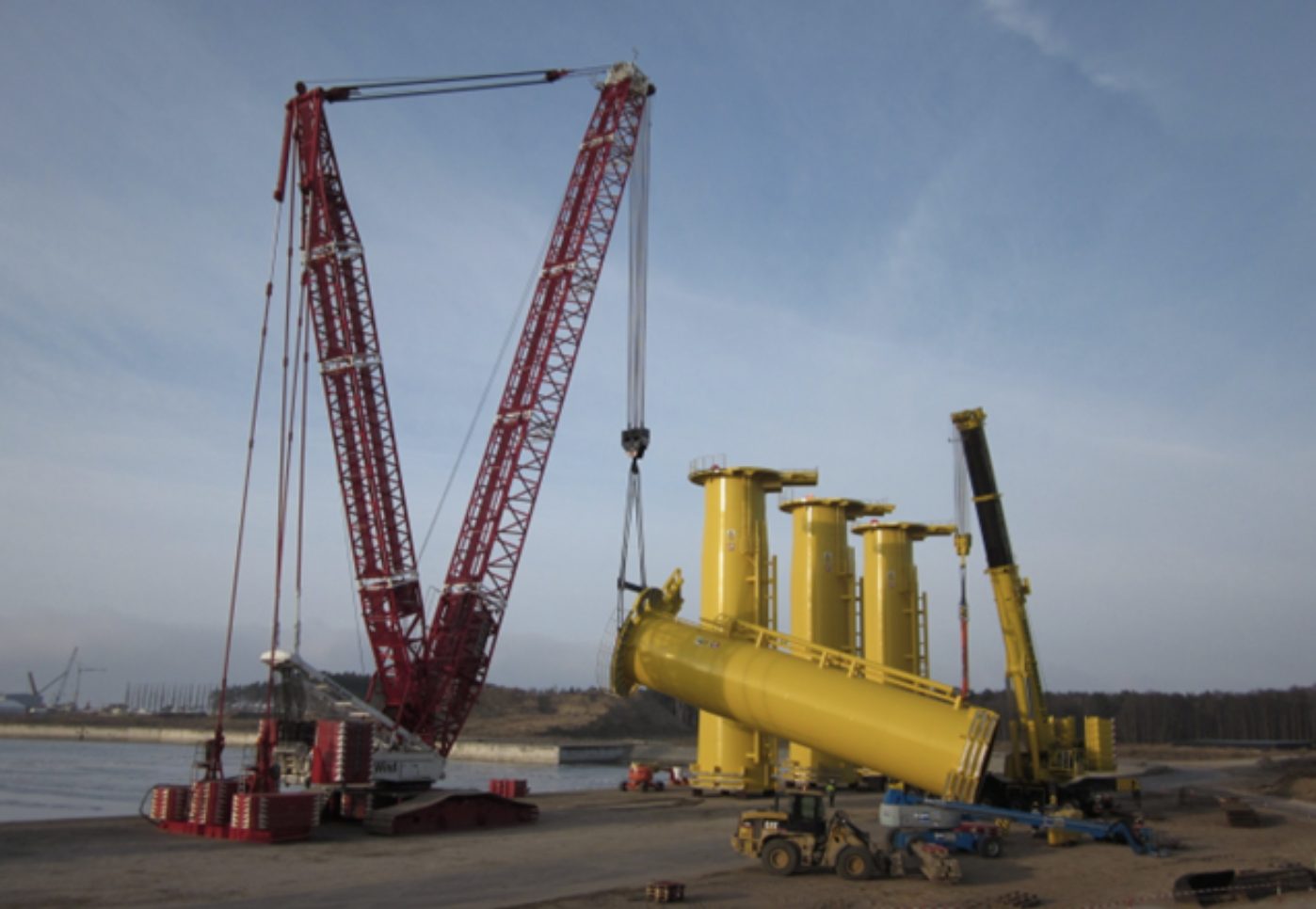 Kran løfter gult transition piece ved havnen i Lubmin