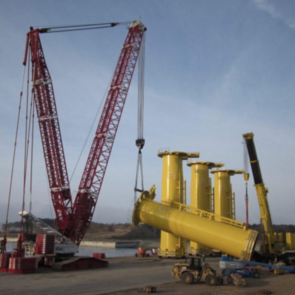 Kran løfter gult transition piece ved havnen i Lubmin