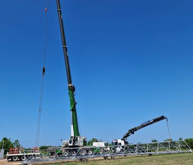 Mobilkran og lastbilkran hejser en telemast i et markareal