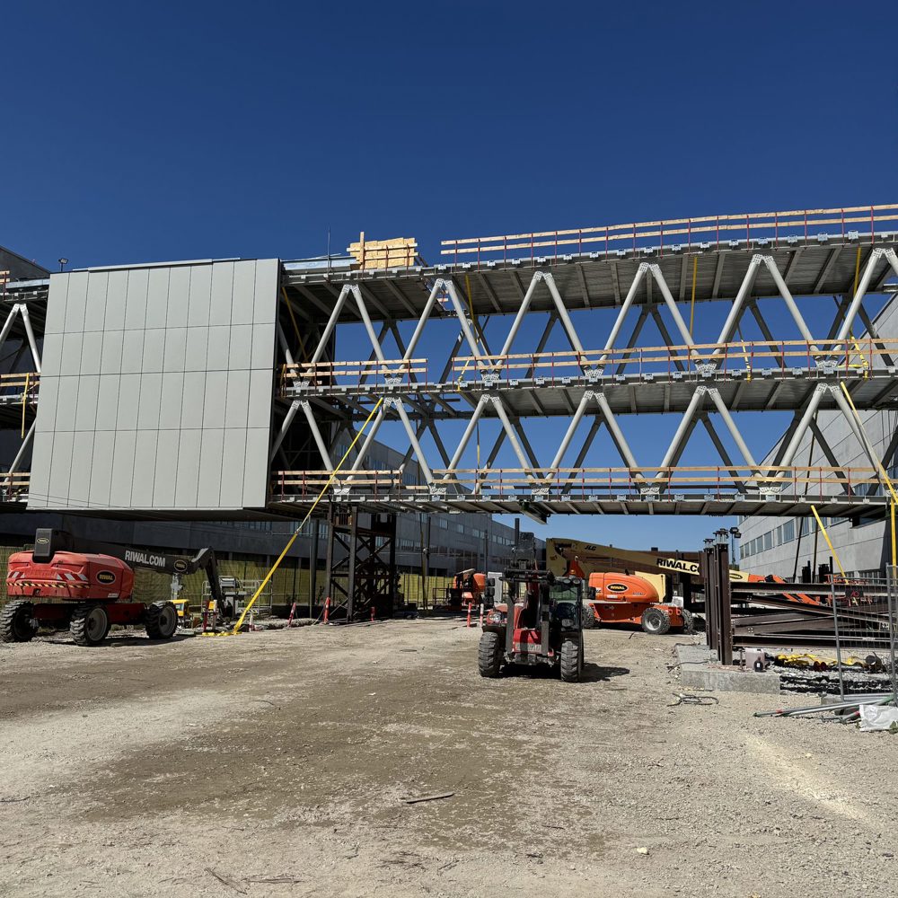 skybridge under opførelse mellem to bygninger, med lifte parkeret nedenunder