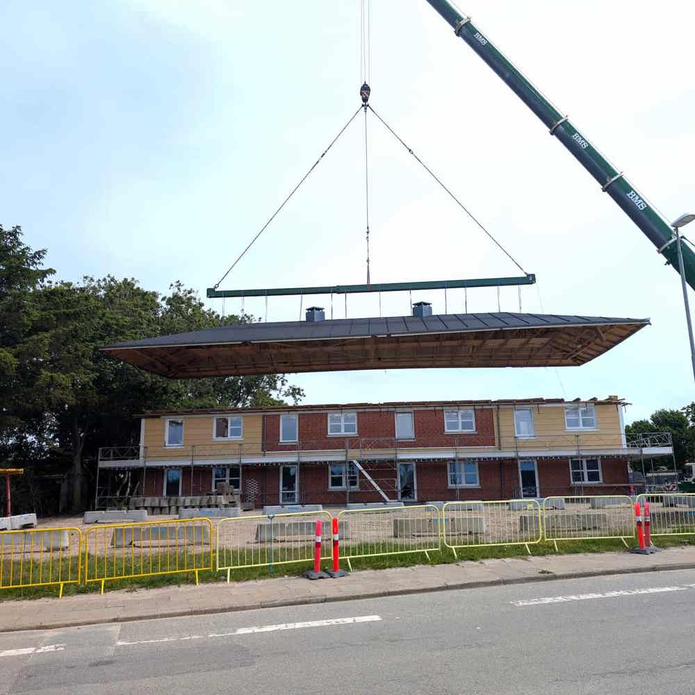 Tagkonstruktion svæver over byggeri, hejst af BMS kran
