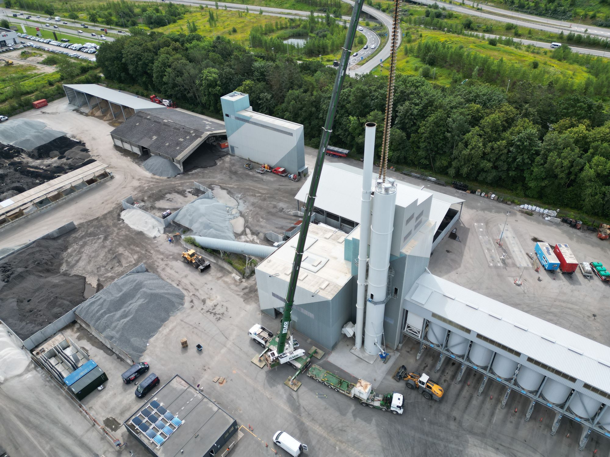 Luftfoto af mobilkran ved industrianlæg i solopgang