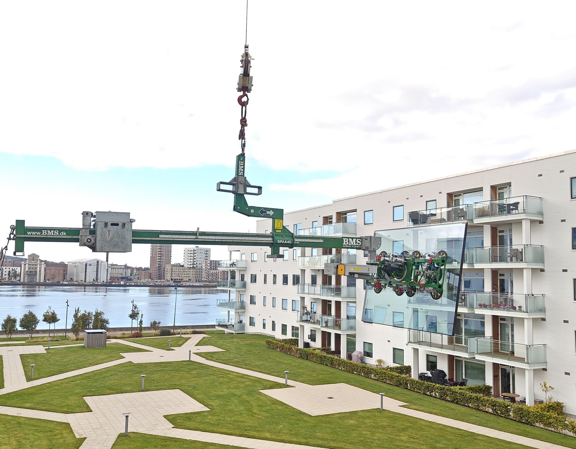 Balanceåg løfter stort glaselement hen til altan på lejlighedsbygning