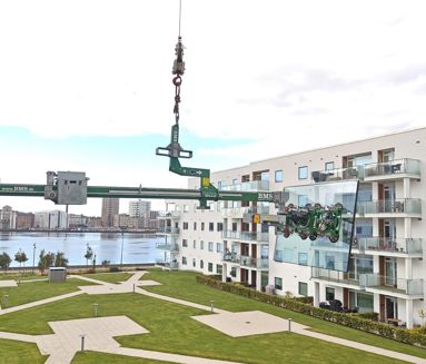 Balanceåg løfter stort glaselement hen til altan på lejlighedsbygning