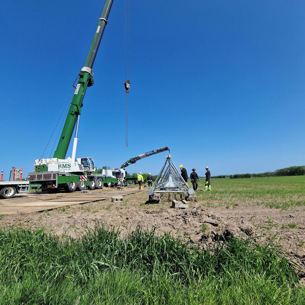 Mobilkran hejser mastefundament på plads i markareal