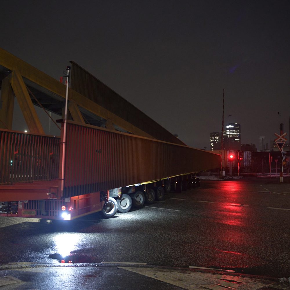 Selvkørende modultransporter (SPMT) kører en stor stål-gangbro gennem Aarhus Havn om natten i sne
